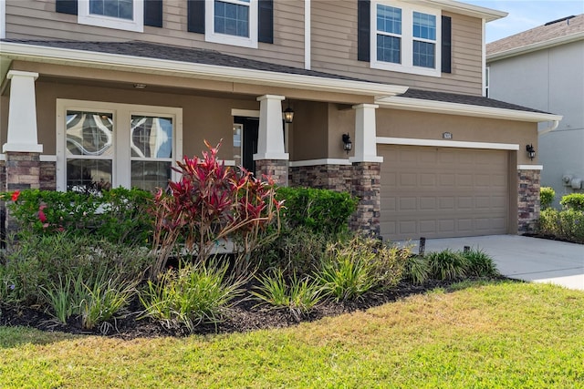 view of front of property with an attached garage, stone siding, a porch, and driveway