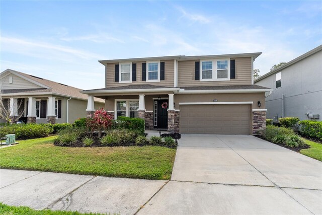 view of front of property with stone siding, an attached garage, a front yard, and concrete driveway
