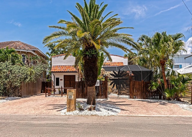 view of front facade featuring a fenced front yard, a gate, a tile roof, stucco siding, and a lanai