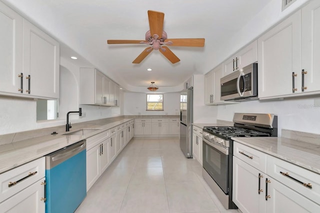 kitchen with stainless steel appliances, a sink, light stone countertops, recessed lighting, and a ceiling fan