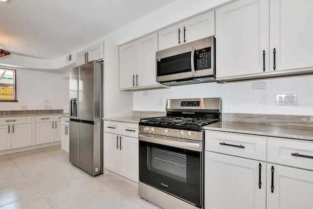 kitchen with stainless steel appliances, light tile patterned floors, and white cabinetry