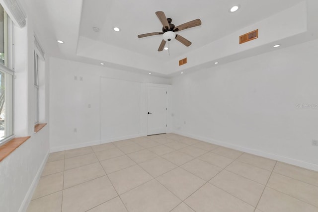 unfurnished room featuring a tray ceiling, recessed lighting, a ceiling fan, light tile patterned flooring, and baseboards