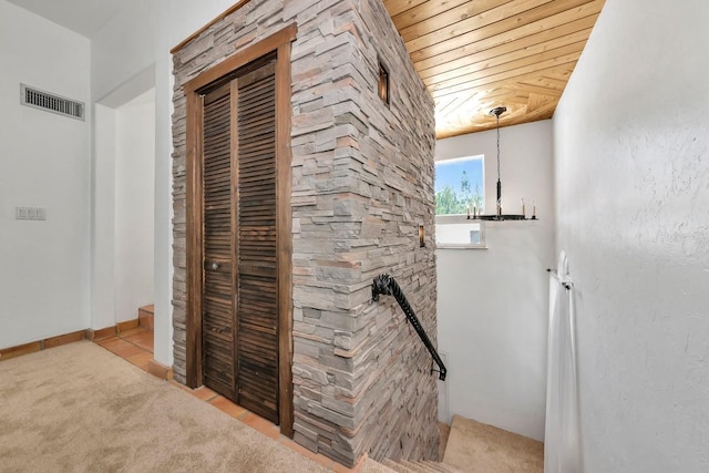 hall featuring wooden ceiling, an upstairs landing, and carpet floors