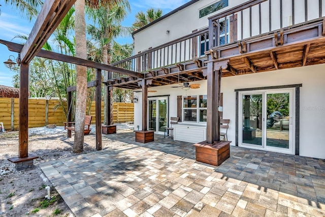 view of patio / terrace featuring fence, a balcony, ceiling fan, and french doors