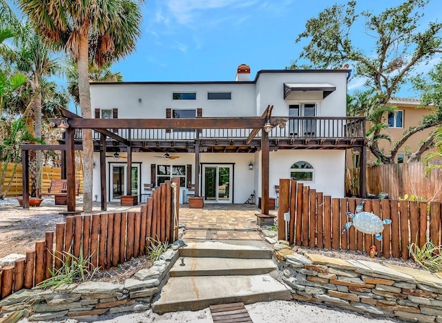 view of front of house featuring stucco siding, fence, and ceiling fan