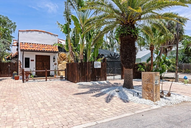 view of front of property featuring a tile roof, a gate, a fenced front yard, and stucco siding