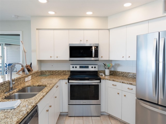 2400 N Beach Rd Unit 1, Englewood, FL 34223 - kitchen featuring appliances with stainless steel finishes, a sink, tasteful backsplash, white cabinets, and light stone counters