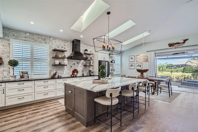 11367 Perico Isle Cir, Bradenton, FL 34209 - kitchen with wall chimney exhaust hood, a skylight, plenty of natural light, a center island, and lofted ceiling