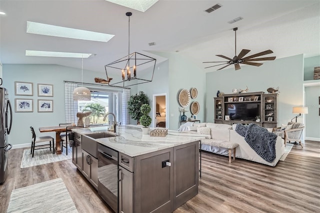 11367 Perico Isle Cir, Bradenton, FL 34209 - kitchen with light wood-style floors, dishwasher, light stone counters, a skylight, and open floor plan