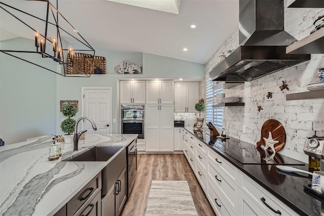 11367 Perico Isle Cir, Bradenton, FL 34209 - kitchen with wall chimney range hood, appliances with stainless steel finishes, backsplash, light stone countertops, and a sink