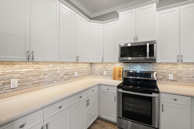 2808 124th Ave E, Parrish, FL 34219 - kitchen with stainless steel appliances, light countertops, white cabinets, and ornamental molding