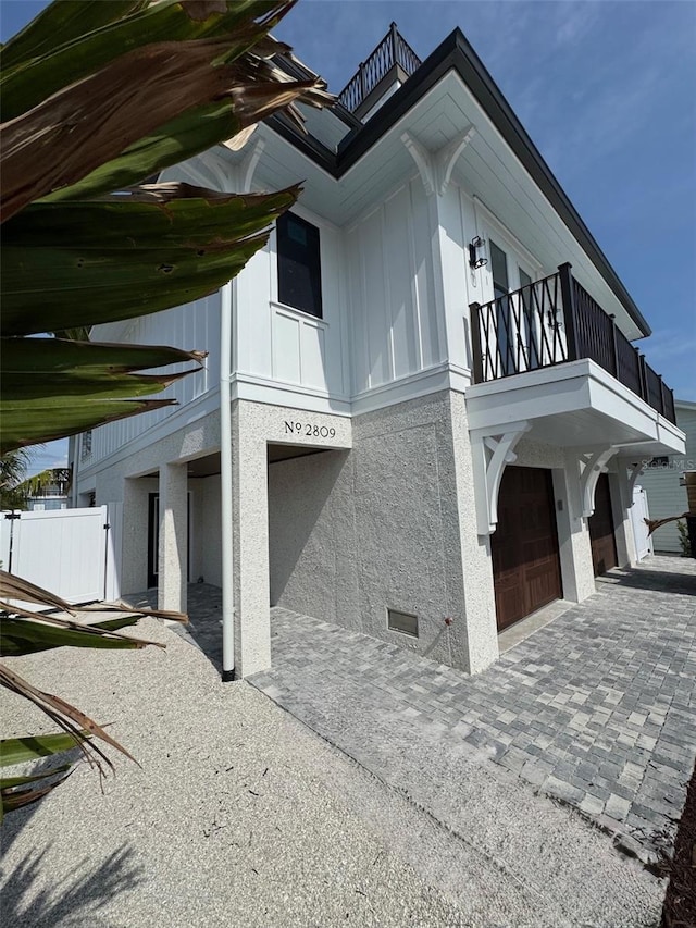 2809 Avenue Ave E, Holmes Beach, FL 34217 - view of home's exterior with a balcony, an attached garage, board and batten siding, and decorative driveway