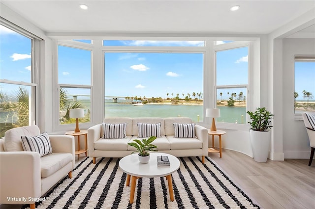 sunroom with a water view, wood finished floors, recessed lighting, and baseboards