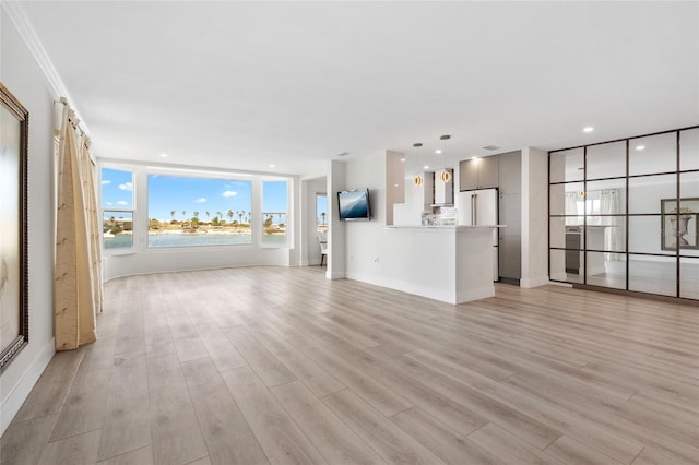 unfurnished living room with light wood-style floors, recessed lighting, ornamental molding, and baseboards
