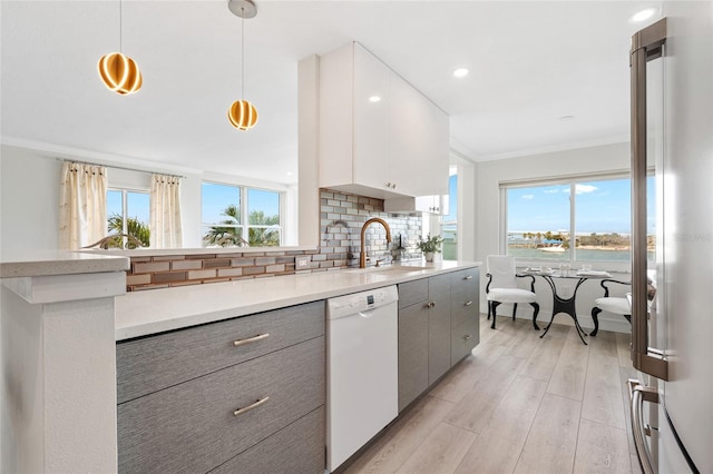 kitchen featuring dishwasher, a sink, gray cabinetry, ornamental molding, and plenty of natural light