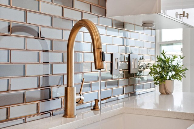 detailed view of decorative backsplash, a sink, and light stone countertops