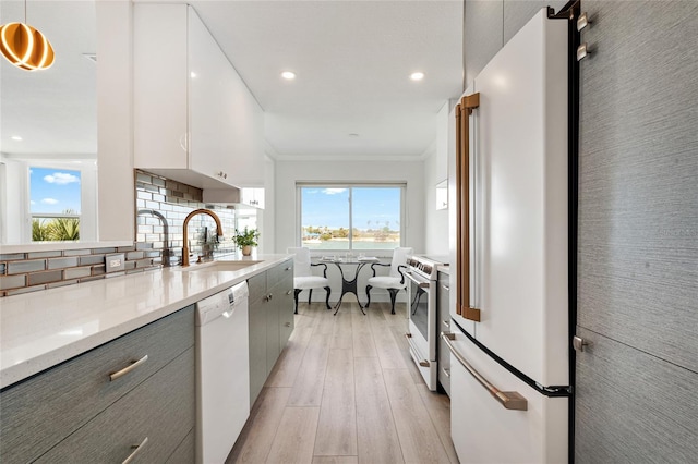 kitchen with white appliances, a sink, gray cabinetry, light wood-type flooring, and healthy amount of natural light