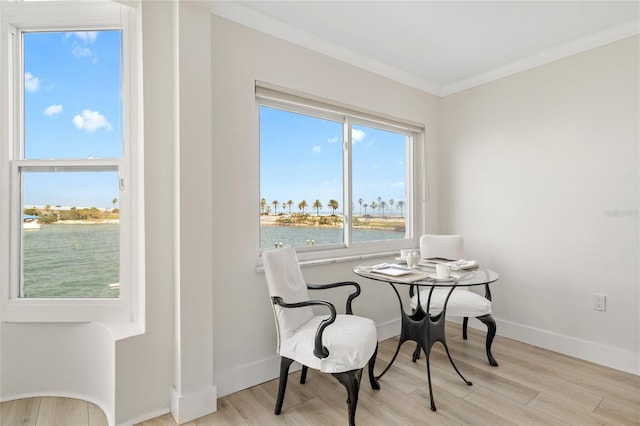 dining area featuring a water view, crown molding, wood finished floors, and baseboards