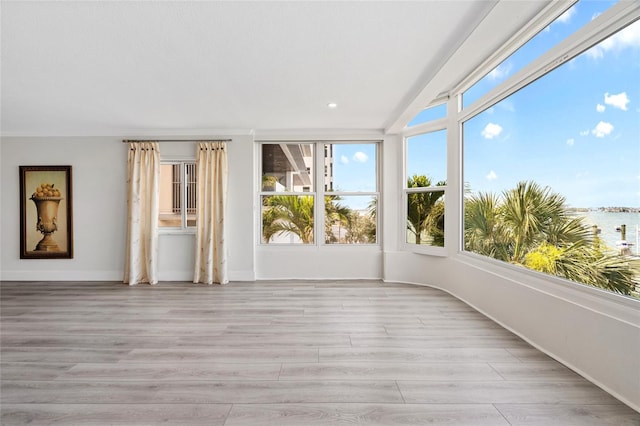 unfurnished sunroom with wood finished floors, baseboards, lofted ceiling, and recessed lighting