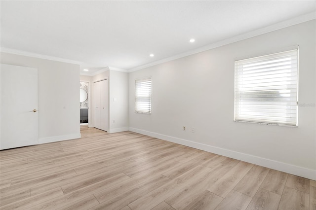 empty room with light wood finished floors, crown molding, baseboards, and recessed lighting
