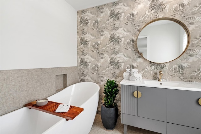 bathroom with wallpapered walls, vanity, and a soaking tub