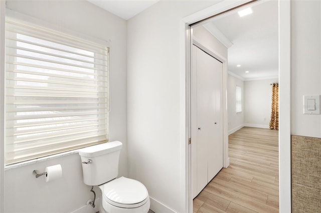 bathroom with wood finished floors, toilet, ornamental molding, and baseboards