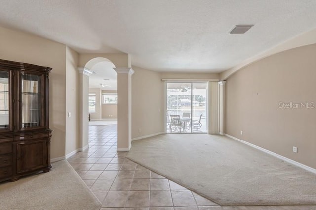 12007 Clubhouse Dr, Lakewood Ranch, FL 34202 - empty room with decorative columns, arched walkways, light tile patterned floors, light carpet, and baseboards