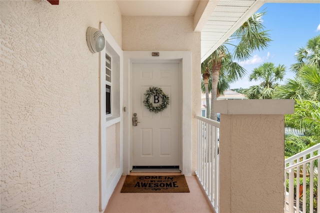 entrance to property with stucco siding and a balcony