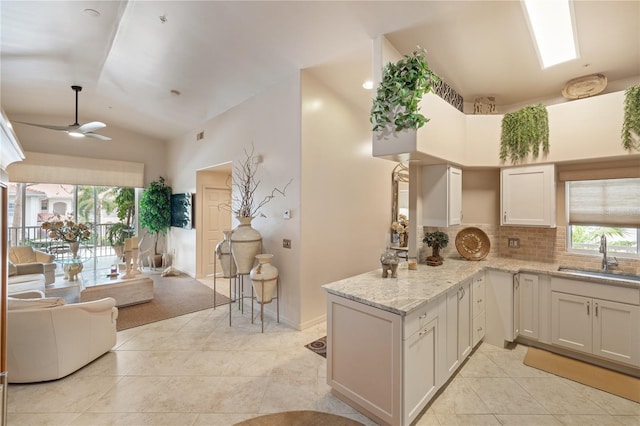 kitchen featuring a sink, open floor plan, light tile patterned floors, healthy amount of natural light, and high vaulted ceiling