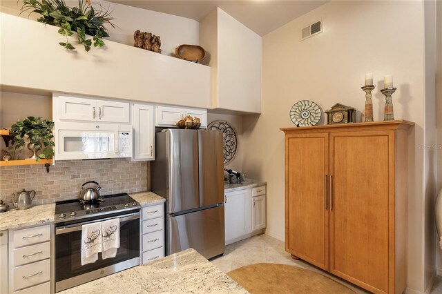 kitchen featuring stainless steel appliances, tasteful backsplash, open shelves, light stone counters, and white cabinetry