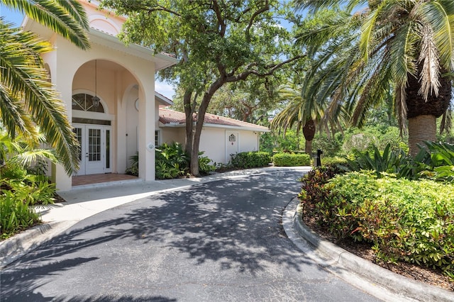 doorway to property with stucco siding, french doors, and a tile roof