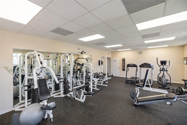 gym with a drop ceiling and baseboards