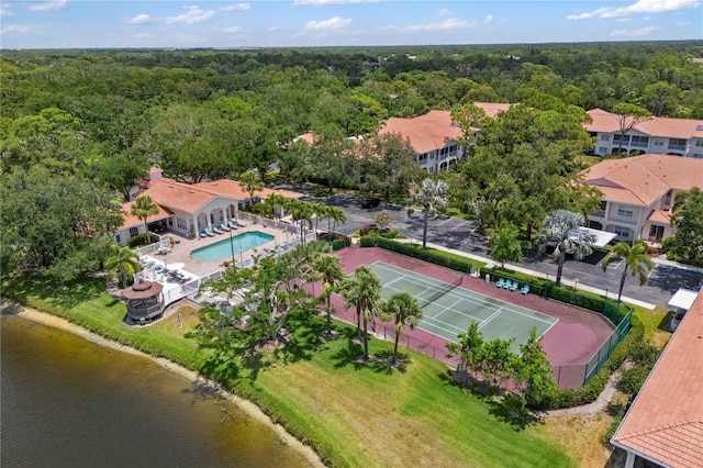 bird's eye view of a heavily wooded area, a pool, and a large body of water