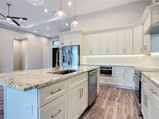 7152 Bougainvillea St, Englewood, FL 34224 - kitchen featuring stainless steel appliances, a sink, ceiling fan, a center island with sink, and light wood-type flooring