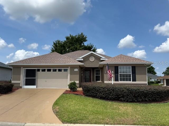 single story home with a garage, concrete driveway, stucco siding, and a front lawn