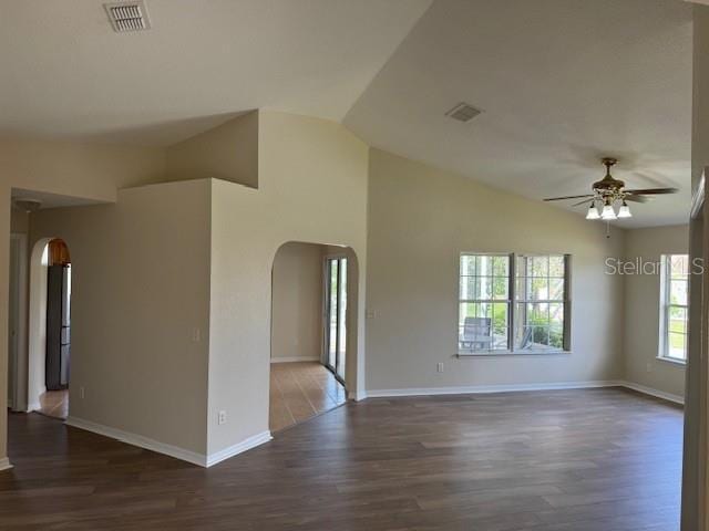 unfurnished room with arched walkways, a ceiling fan, wood finished floors, baseboards, and lofted ceiling