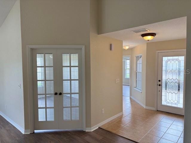 entrance foyer with french doors, baseboards, and tile patterned floors