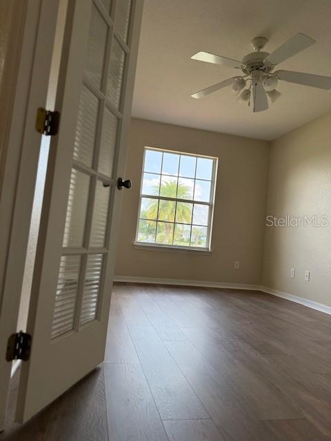 unfurnished room featuring baseboards, wood finished floors, and a ceiling fan
