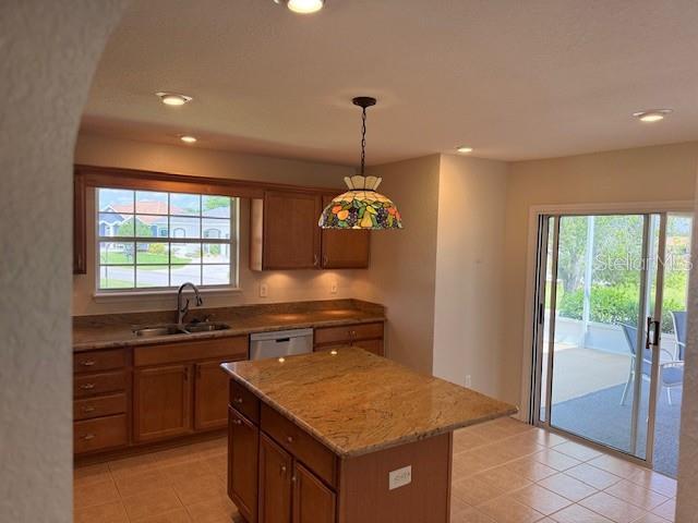 kitchen with a sink, brown cabinetry, light tile patterned floors, dishwasher, and recessed lighting