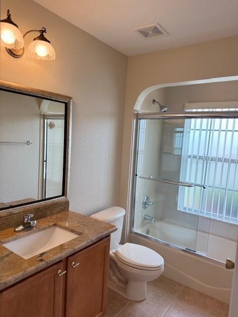 full bath with vanity, enclosed tub / shower combo, toilet, and tile patterned floors
