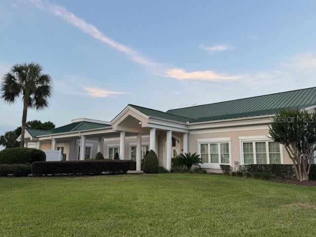 view of front of property with a front lawn, metal roof, and stucco siding