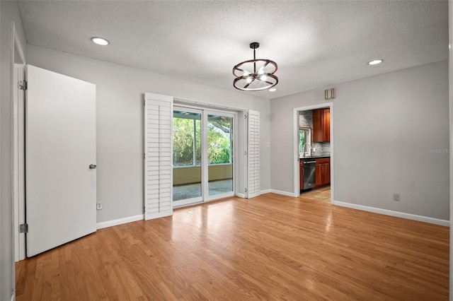 6512 Bowline Dr, Sarasota, FL 34231 - unfurnished dining area featuring a chandelier, light wood-style floors, a textured ceiling, baseboards, and recessed lighting