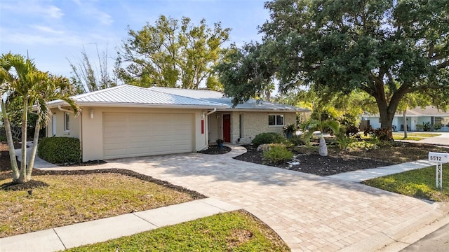 6512 Bowline Dr, Sarasota, FL 34231 - view of front of house featuring a garage, decorative driveway, metal roof, stucco siding, and stone siding