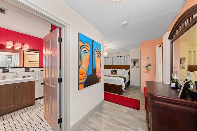 941 Virginia Dr, Sarasota, FL 34234 - bedroom featuring a sink, baseboards, light wood-type flooring, and connected bathroom