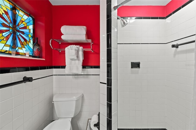 941 Virginia Dr, Sarasota, FL 34234 - bathroom featuring tiled shower, toilet, a wainscoted wall, and tile walls