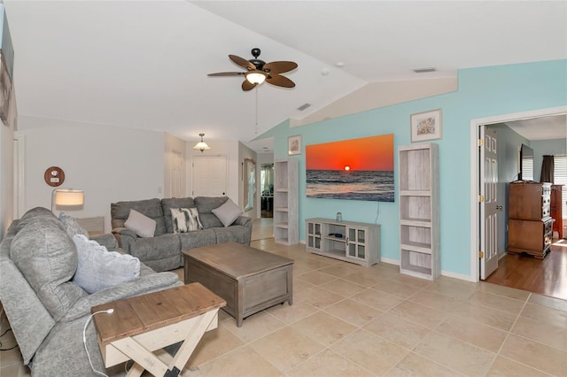 living area with a ceiling fan, vaulted ceiling, light tile patterned floors, and baseboards