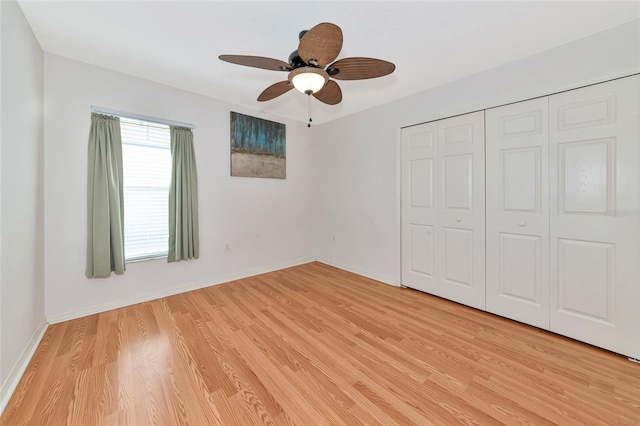 unfurnished bedroom with light wood-style flooring, a closet, a ceiling fan, and baseboards
