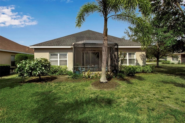 back of property with stucco siding, a lawn, and a shingled roof