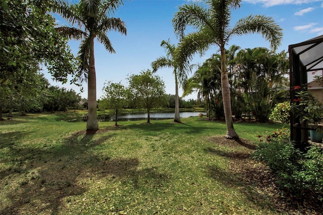 view of green lawn featuring a water view and a lanai