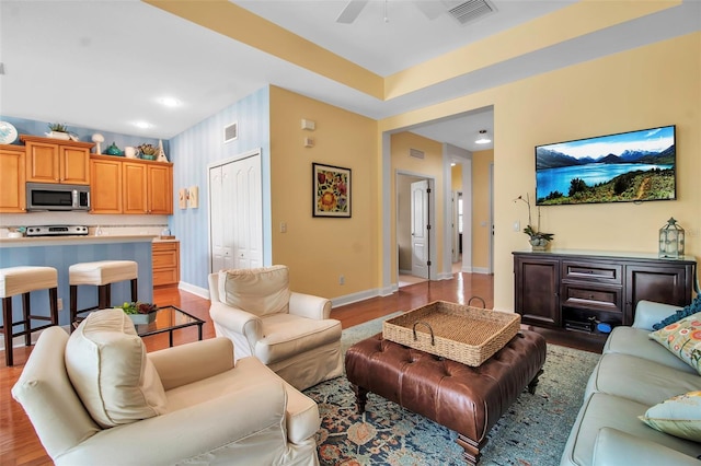 living area featuring a ceiling fan, light wood-type flooring, and baseboards